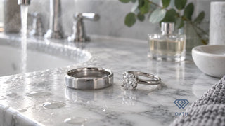 Platinum wedding band beside a white gold diamond solitaire on a marble bathroom vanity